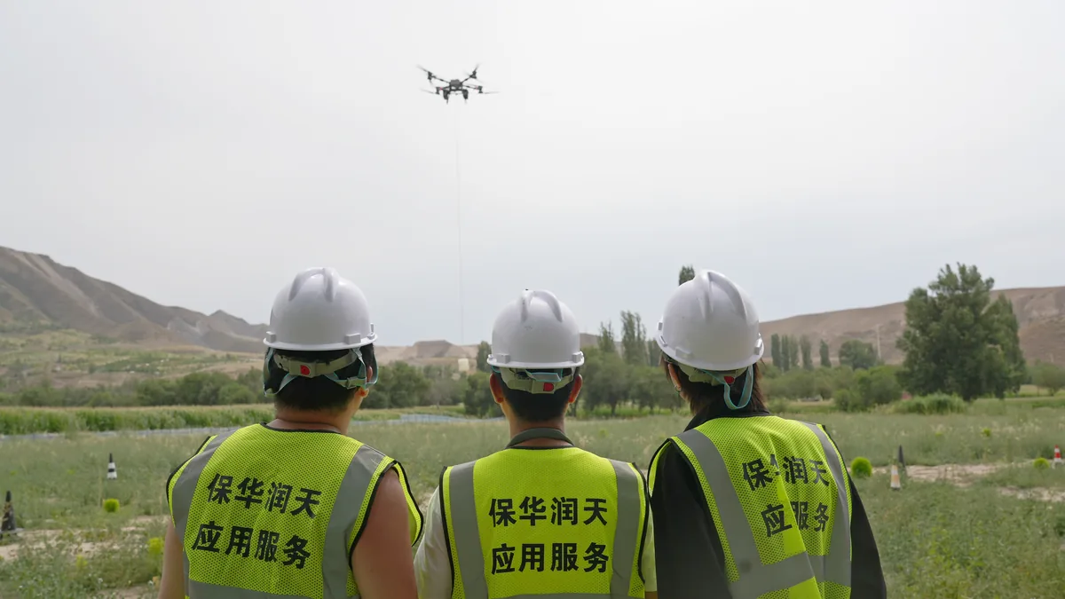 学员佩戴安全帽观察重载无人机吊运飞行